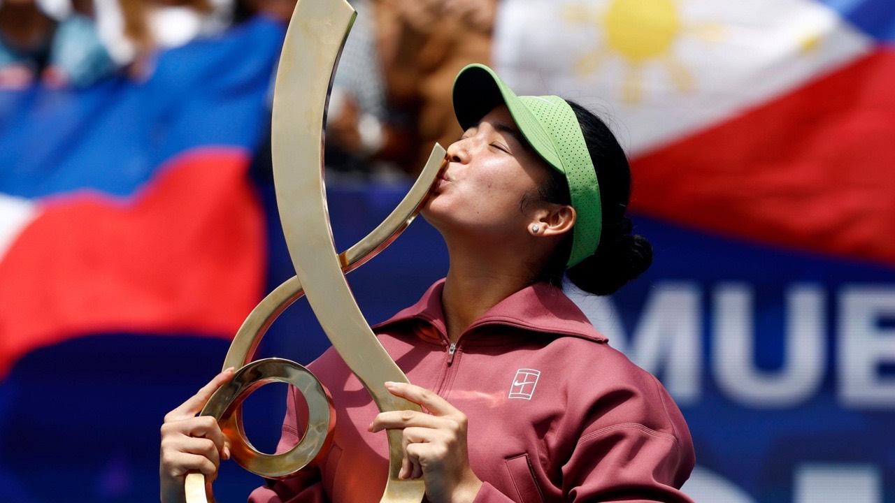 Alex Eala kisses the Washington DC Open trophy in front of Philippine flags